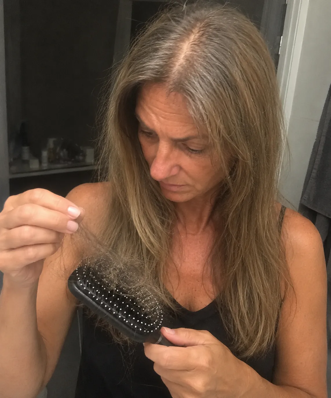 Žena se dívá na vlasy zachycené v kartáči